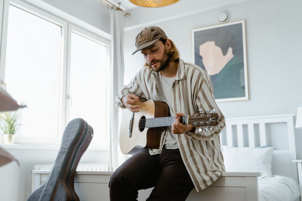 man in brown and white long sleeves shirt playing acoustic guitar