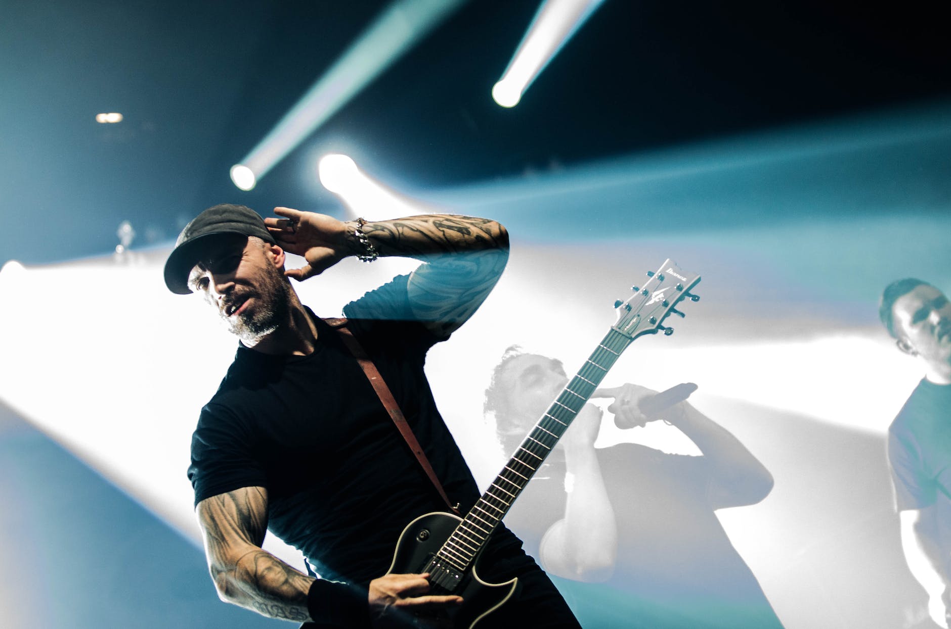 man in black crew neck shirt holding a black electric guitar