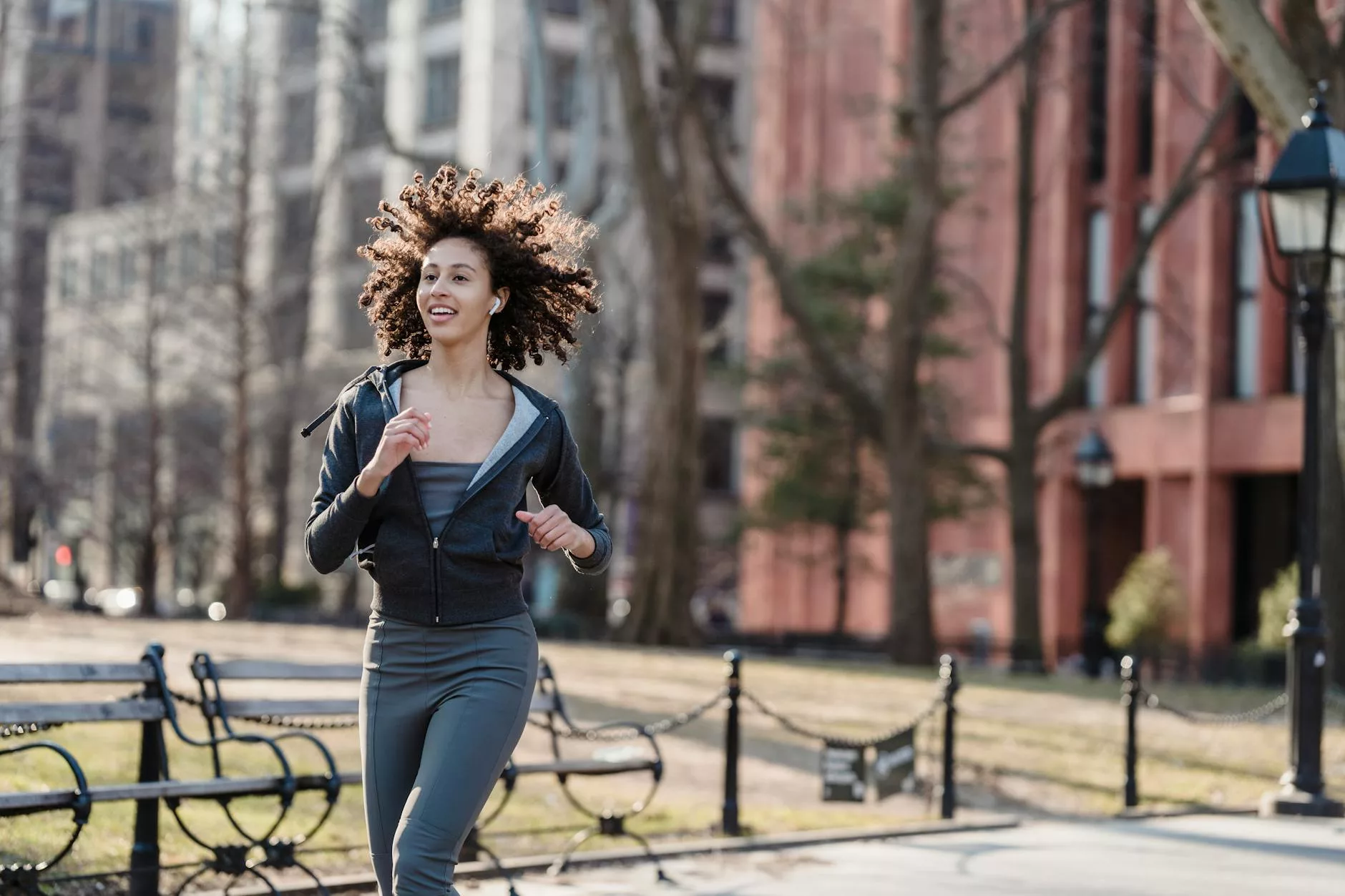 positive ethnic woman running on city street