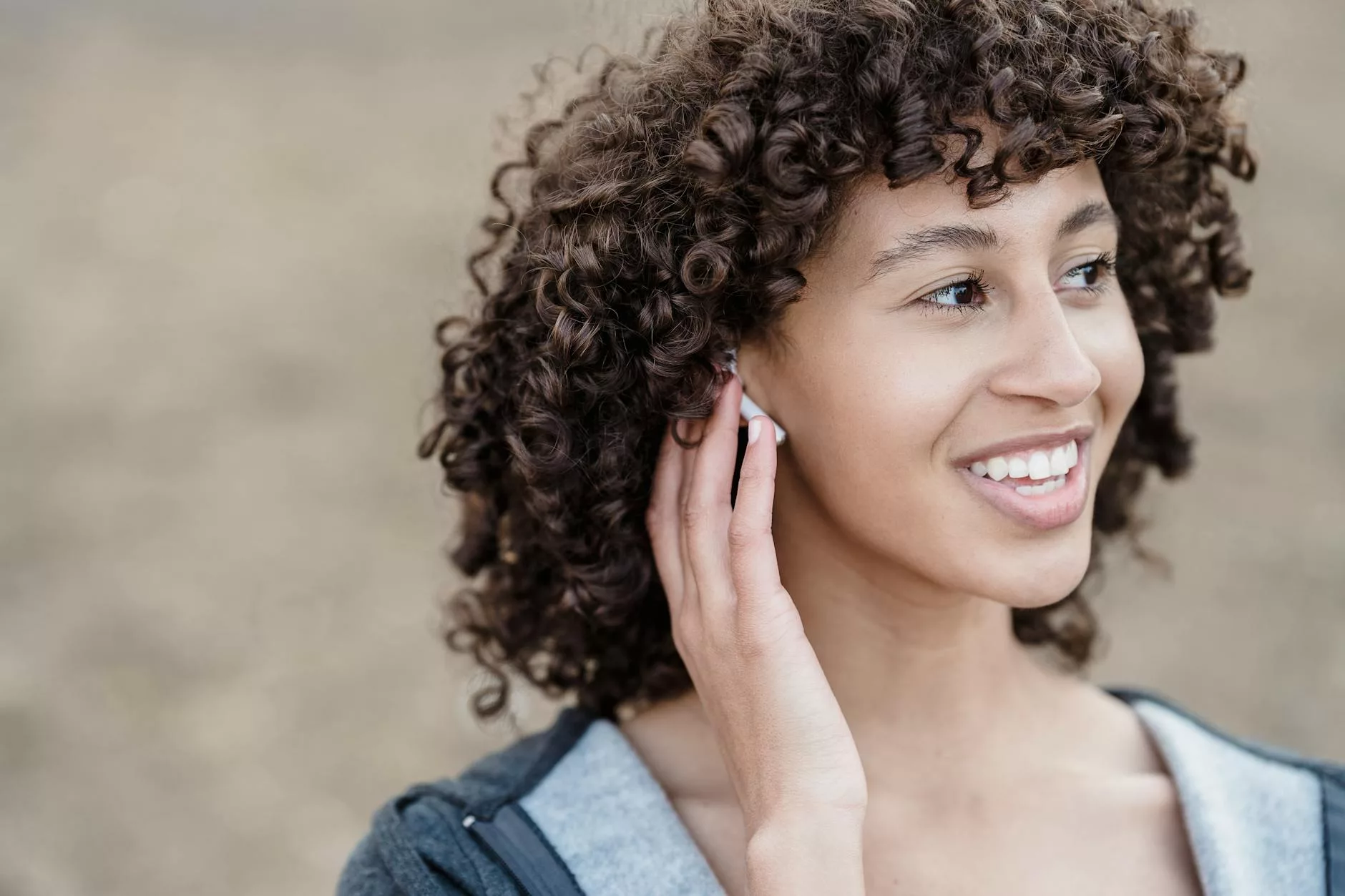 happy ethnic woman listening to music in wireless earbuds