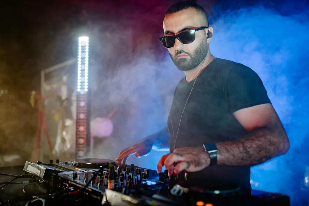 man in zwart T-shirt en zwarte zonnebril die een audiomixer gebruikt