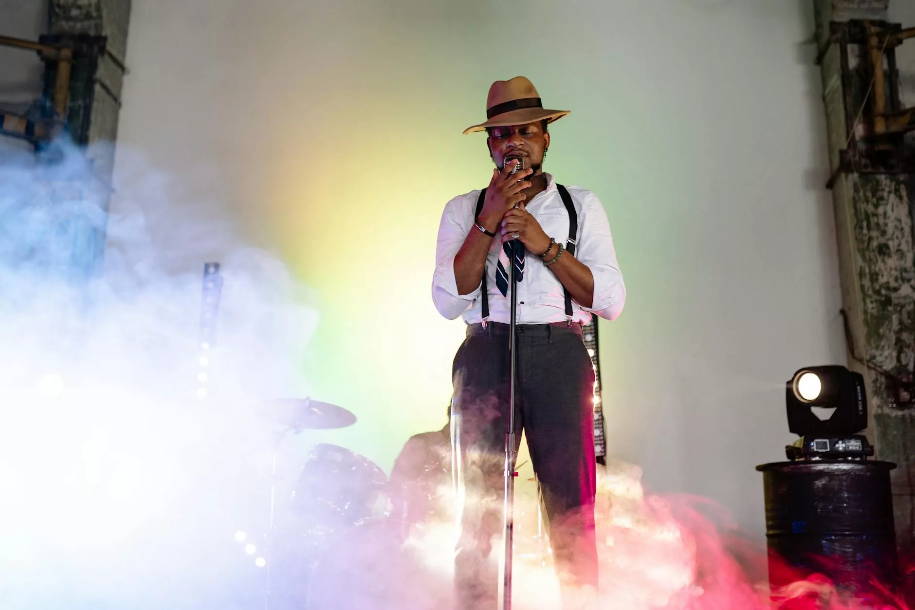 a man in white long sleeve shirt and brown hat singing on stage