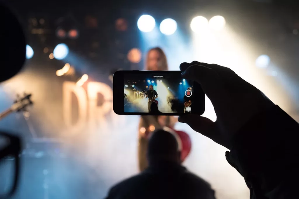 Music video promotion budget tips - person taking photo of man on stage